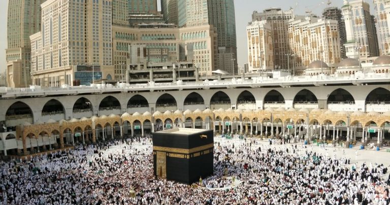 The Kaaba at the center of the Grand Mosque, surrounded by thousands of pilgrims in white ihram.