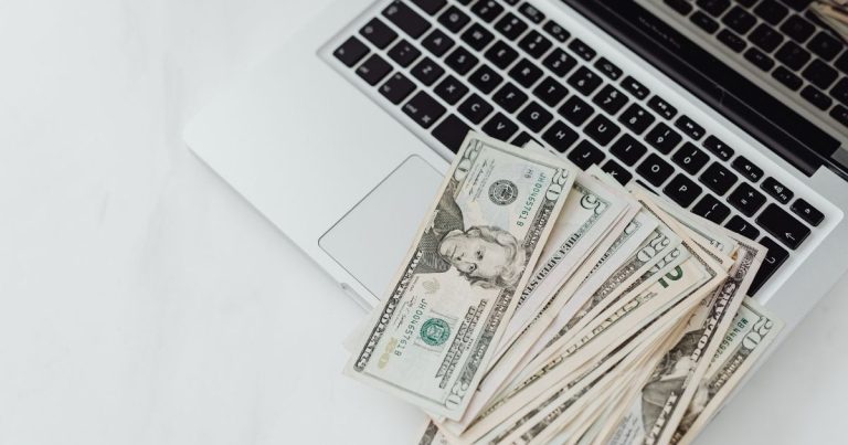 Stack of US dollar bills on a laptop keyboard.