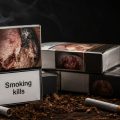 Several cigarette packs with a prominent 'Smoking kills' warning, ashes and cigarettes scattered on a dark wooden surface.