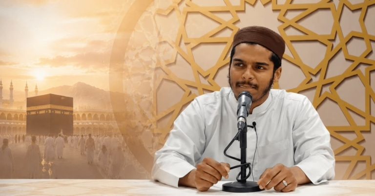 Man in a white robe speaks into a microphone at a desk, with a gold geometric backdrop and a Kaaba scene in the background.