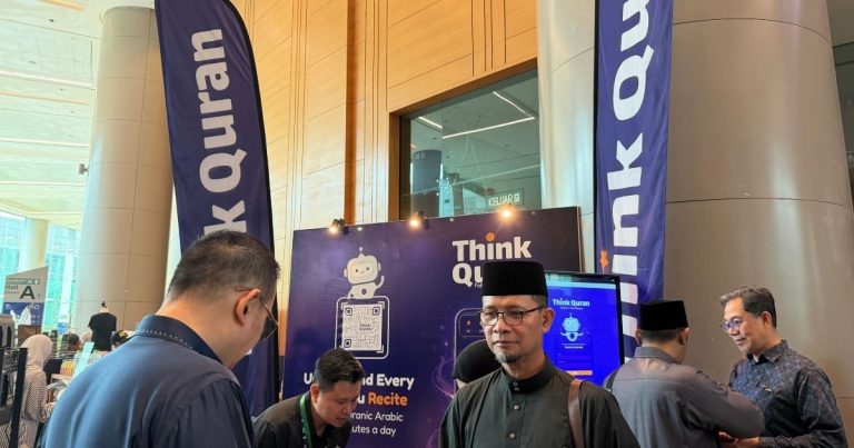 Group of men at an indoor expo booth with Think Quran display and tall blue banners reading Think Quran.