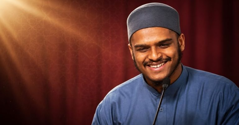 Seni Membina Hubungan: 5 Rahsia Disukai Ramai Ikut Sunnah | Denaihati Smiling man in a blue shirt and gray cap speaks into a microphone on stage.