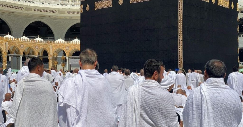 Crowd of Muslim pilgrims in white ihram robes circumambulating the Kaaba at Masjid al-Haram in Mecca.