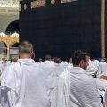 Crowd of Muslim pilgrims in white ihram robes circumambulating the Kaaba at Masjid al-Haram in Mecca.