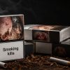 Several cigarette packs with a prominent 'Smoking kills' warning, ashes and cigarettes scattered on a dark wooden surface.