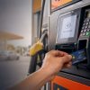 Person inserts a card into a gas pump payment terminal at a fueling station.